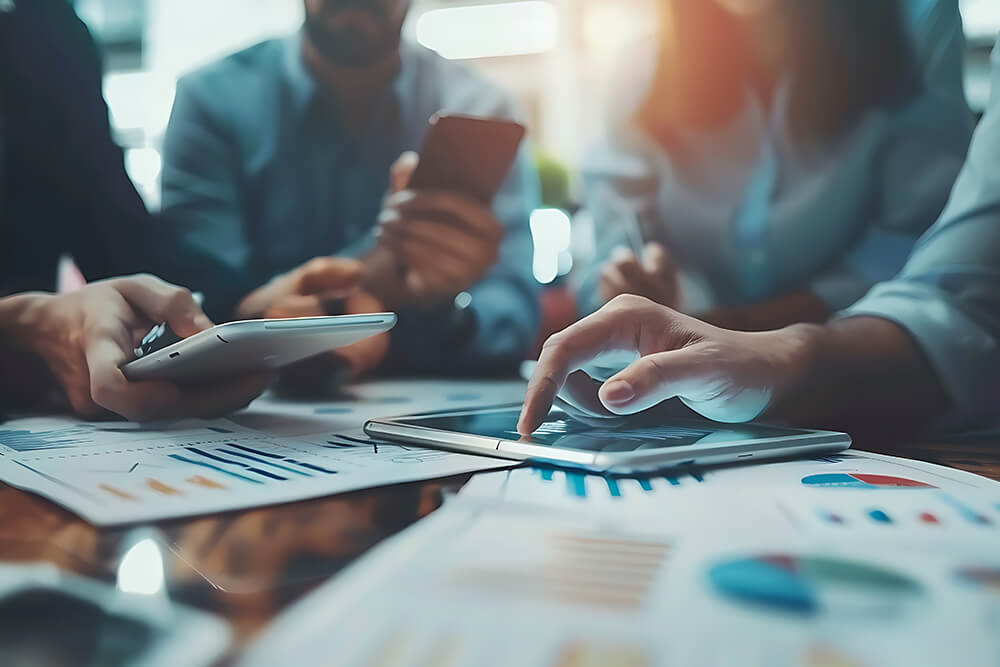 People's hands holding tablets and phones examining charts, illustrating service delivery models and project development strategies