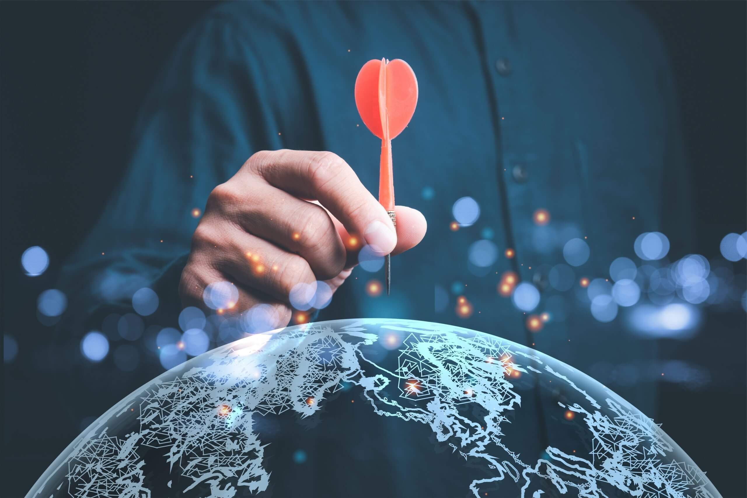 Visual of half a globe with a red dart being aimed at the north pole by a hand, with bokeh elements, representing global reach and precision in TVST’s live value management events